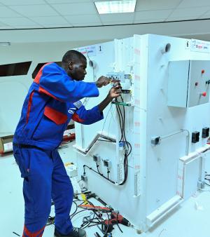 L'apprenti médaillé d'or des épreuves régionales World Skills 2020 Métier Installation Electrique visse un composant sur sa maquette.